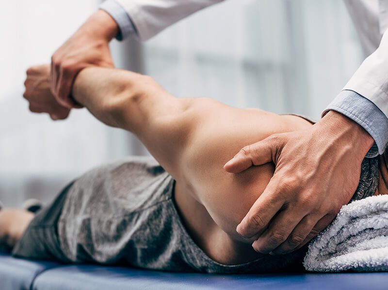 ACG selective focus of chiropractor stretching arm of patient in hospital