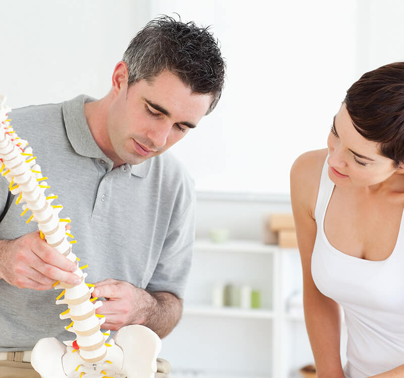 ACG Chiropractor and patient looking at a model of a spine in a room