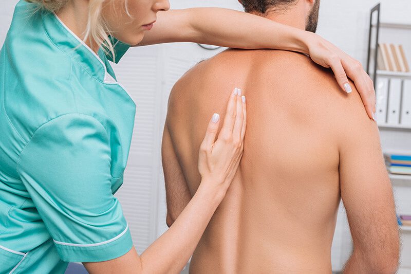 ACG back view of man having chiropractic adjustment in clinic